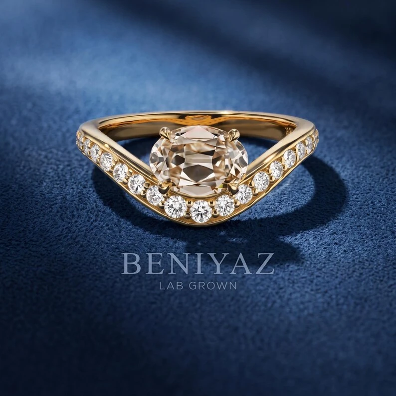 1.66 CT antique oval cut lab grown diamond engagement ring in yellow gold with a sculpted pavé split shank on deep navy blue fabric.