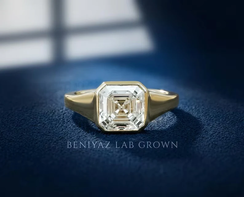 A geometric Asscher cut lab grown diamond framed in a sleek yellow-gold bezel signet silhouette.